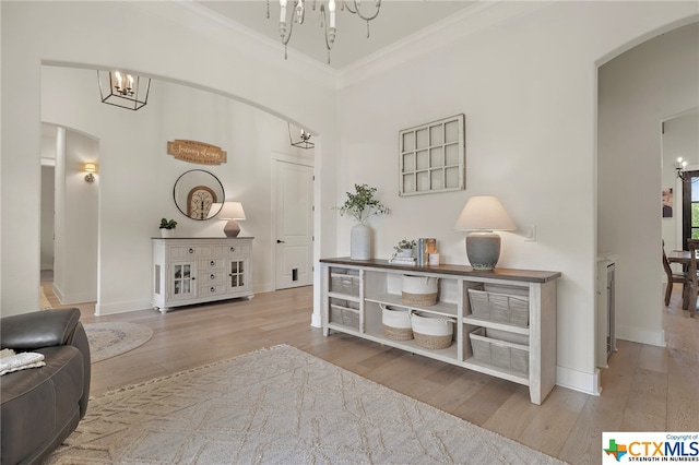 hallway with hardwood / wood-style flooring, ornamental molding, a high ceiling, and a chandelier