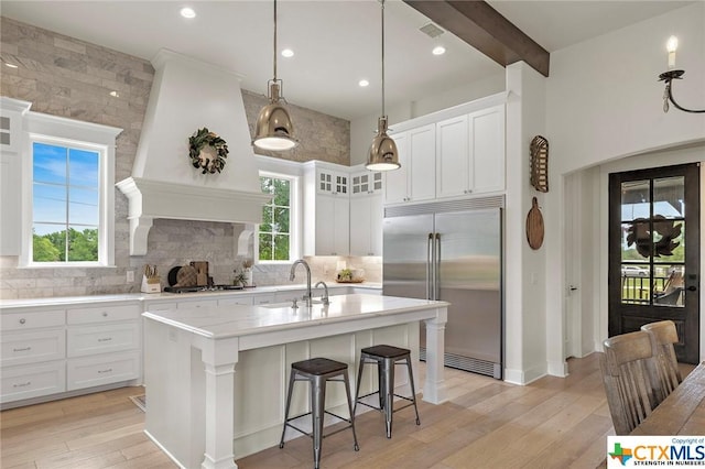 kitchen featuring appliances with stainless steel finishes, pendant lighting, an island with sink, sink, and white cabinets