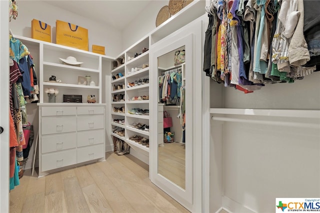 walk in closet with light hardwood / wood-style flooring