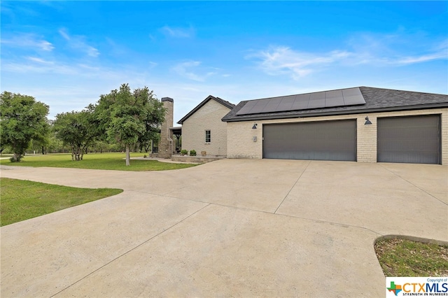 view of front of house with a garage, a front yard, and solar panels