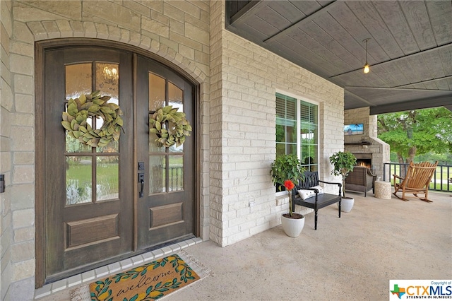 property entrance with a patio area, french doors, and an outdoor fireplace