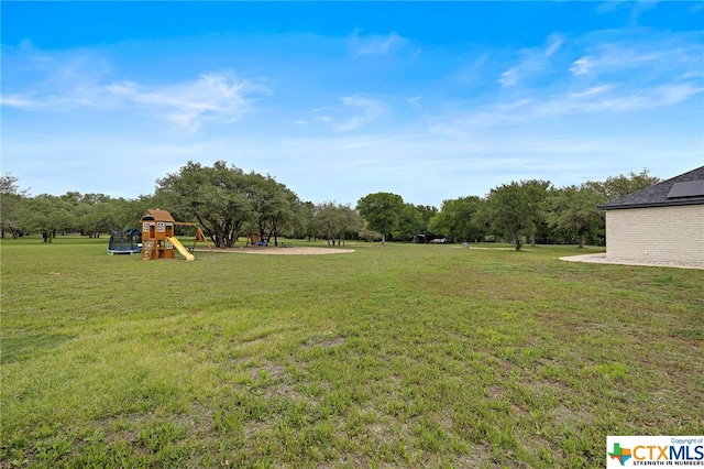 view of yard featuring a trampoline and a playground