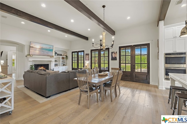 dining area featuring beam ceiling, a notable chandelier, light hardwood / wood-style floors, and french doors