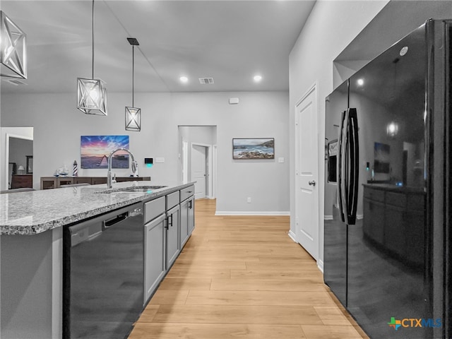 1525 Dryden Ave, Copperas Cove, TX 76522 - kitchen featuring black appliances, a sink, light wood-style flooring, hanging light fixtures, and light stone counters