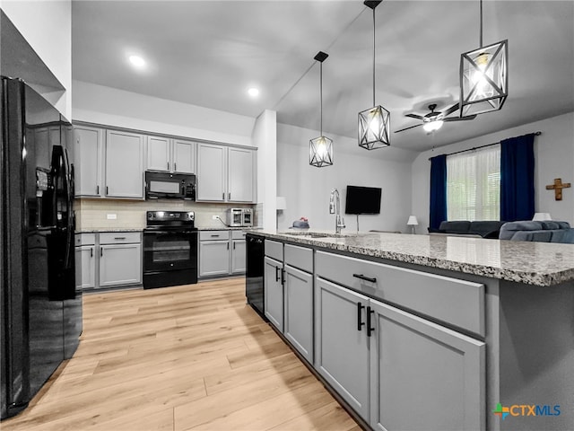 1525 Dryden Ave, Copperas Cove, TX 76522 - kitchen with black appliances, a sink, gray cabinets, open floor plan, and hanging light fixtures