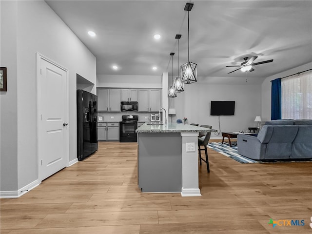 1525 Dryden Ave, Copperas Cove, TX 76522 - kitchen with black appliances, a kitchen breakfast bar, open floor plan, decorative light fixtures, and light wood-style floors