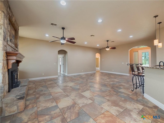 unfurnished living room featuring a wood stove and ceiling fan