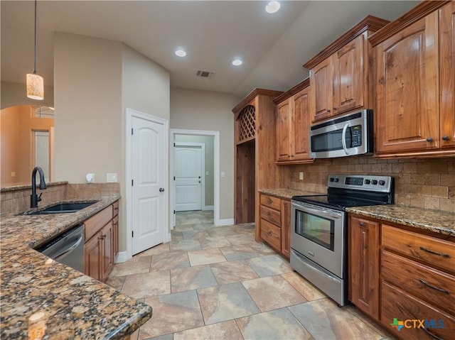 kitchen with decorative backsplash, appliances with stainless steel finishes, dark stone counters, sink, and decorative light fixtures