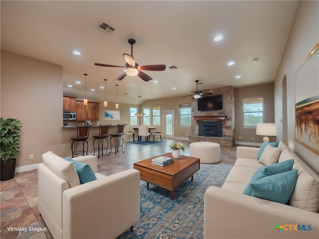 tiled living room with a stone fireplace, a wealth of natural light, and ceiling fan