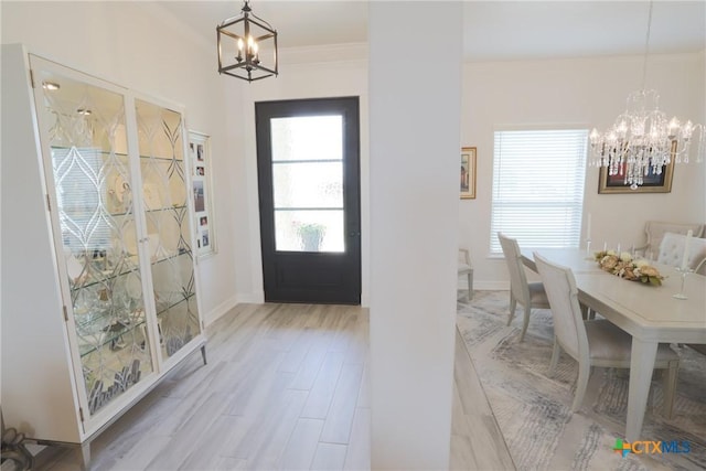 foyer with baseboards, wood finished floors, a notable chandelier, and ornamental molding