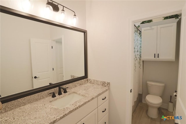 full bath featuring toilet, vanity, and baseboards