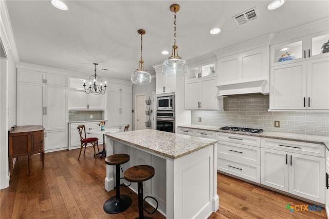 2717 Canyon Oaks Ct, Temple, TX 76502 - kitchen with stainless steel appliances, a center island, white cabinets, backsplash, and hardwood / wood-style flooring