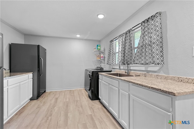 120 Mighty Oak Ln, Killeen, TX 76542 - kitchen featuring freestanding refrigerator, separate washer and dryer, a sink, ornamental molding, and white cabinetry