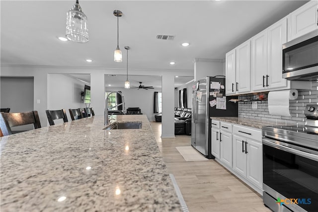 120 Mighty Oak Ln, Killeen, TX 76542 - kitchen with stainless steel appliances, a sink, a ceiling fan, decorative backsplash, and light wood-style floors