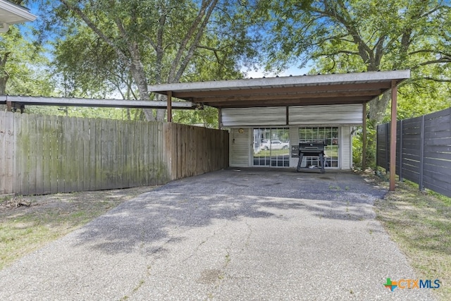 212 Whitfield St, Yoakum, TX 77995 - view of parking featuring asphalt driveway, fence, and a carport