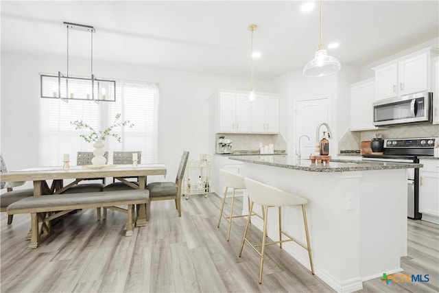 kitchen featuring a center island with sink, white cabinets, and appliances with stainless steel finishes