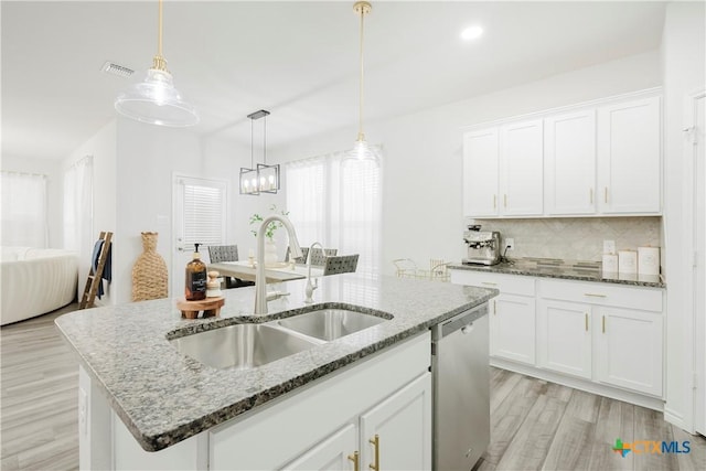 kitchen featuring decorative light fixtures, white cabinetry, dishwasher, sink, and an island with sink