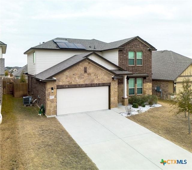 view of front property featuring a garage, central AC unit, and solar panels