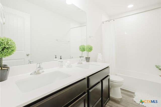 full bathroom featuring hardwood / wood-style flooring, vanity, toilet, and shower / tub combo