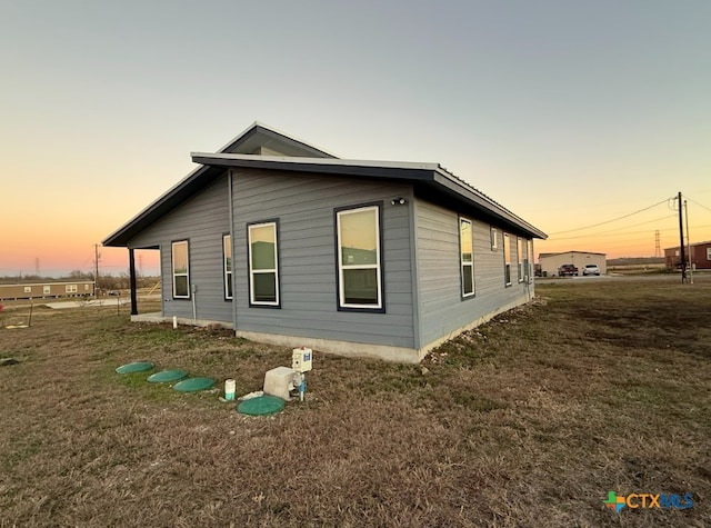 property exterior at dusk with a lawn