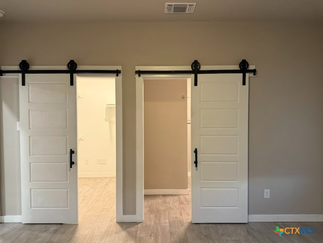 interior space with a barn door and light hardwood / wood-style floors