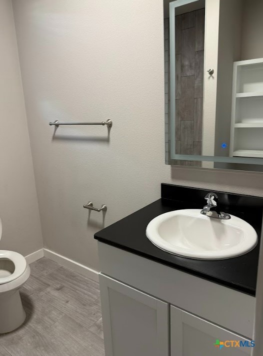 bathroom with hardwood / wood-style floors, vanity, and toilet