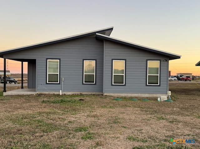 property exterior at dusk with a lawn