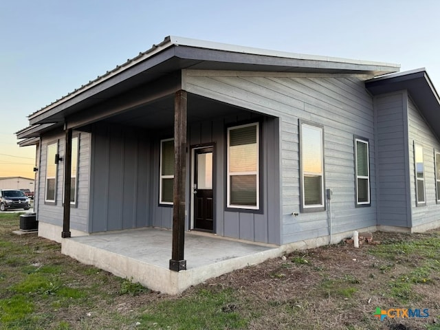 back house at dusk featuring central air condition unit and a patio area