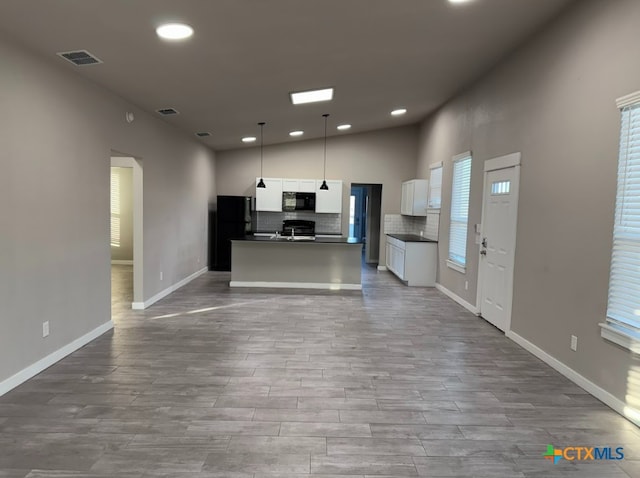 kitchen with white cabinetry, pendant lighting, decorative backsplash, a center island with sink, and black appliances