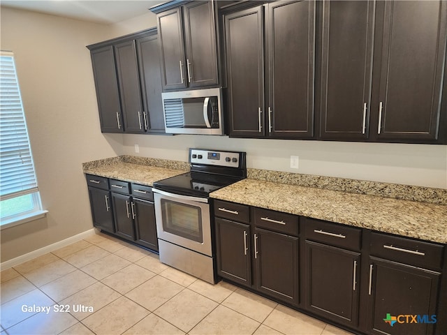 kitchen with light stone counters, light tile patterned flooring, and stainless steel appliances