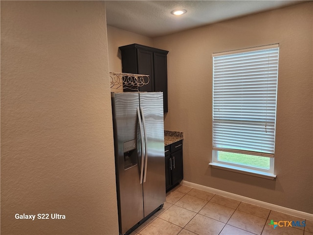 kitchen featuring stainless steel refrigerator with ice dispenser, light stone counters, and light tile patterned flooring