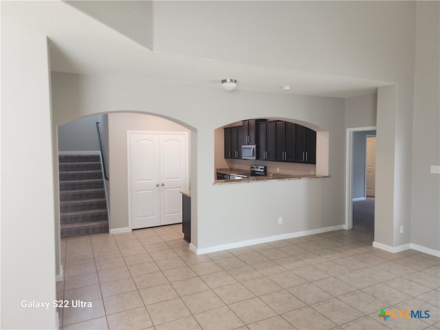 kitchen with light tile patterned flooring, kitchen peninsula, and appliances with stainless steel finishes