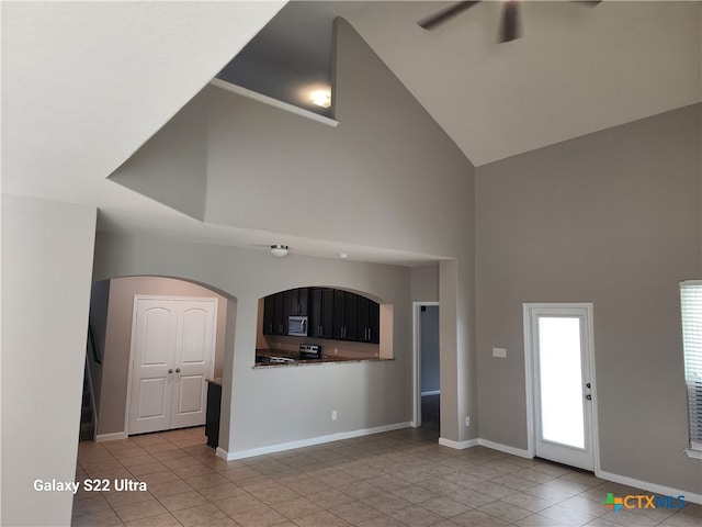 unfurnished living room with ceiling fan, a towering ceiling, and light tile patterned floors