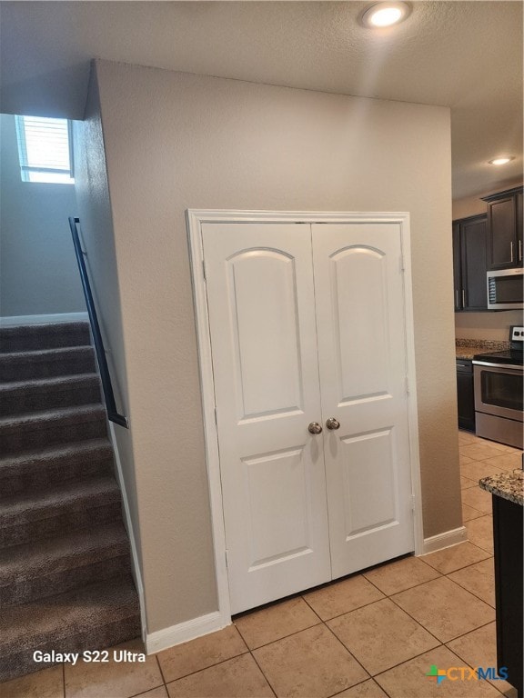 kitchen with light tile patterned flooring, light stone countertops, and stainless steel appliances