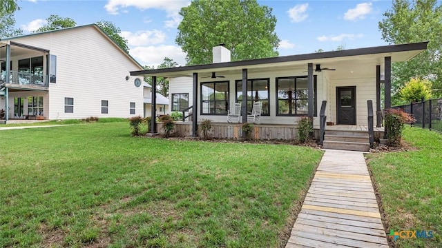 rear view of house with fence, ceiling fan, a porch, a chimney, and a yard