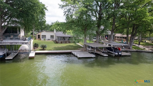 view of dock featuring a water view, boat lift, and a yard