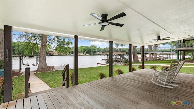 deck with a water view, ceiling fan, and a yard