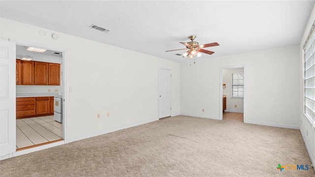 unfurnished bedroom featuring baseboards, ensuite bathroom, light carpet, and visible vents