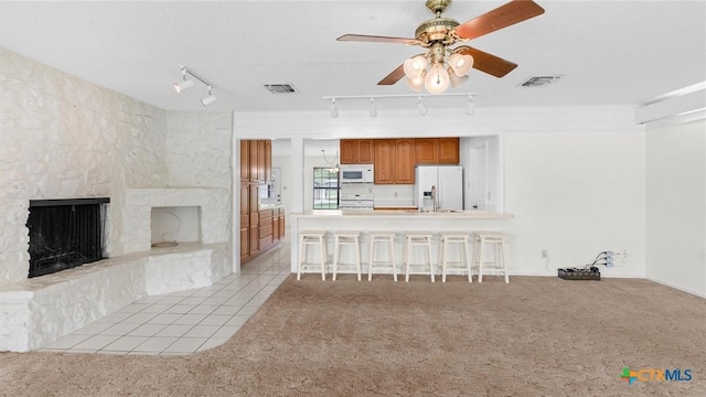 living room with track lighting, ceiling fan, light colored carpet, and visible vents