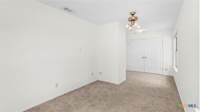 carpeted spare room featuring visible vents and baseboards