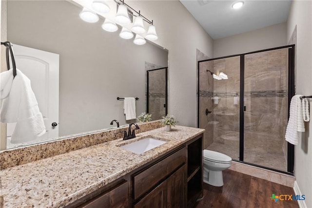 full bath featuring vanity, a shower stall, toilet, and wood finished floors