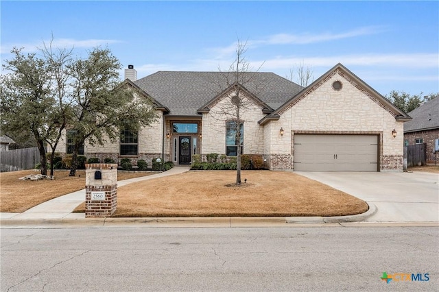 french country home featuring a garage, driveway, a chimney, and fence