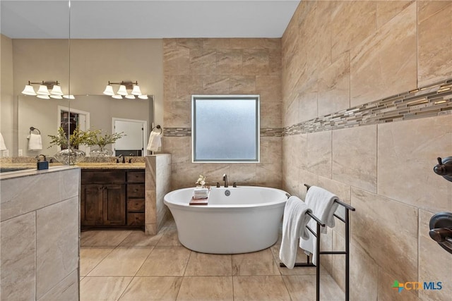 bathroom with tile patterned floors, tile walls, a freestanding bath, and vanity