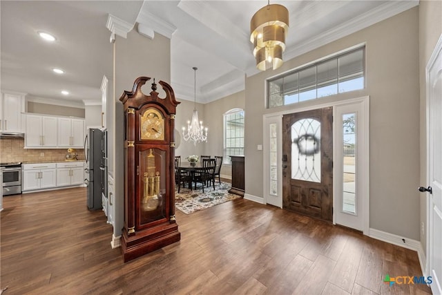 entryway featuring crown molding, baseboards, dark wood-type flooring, and a notable chandelier