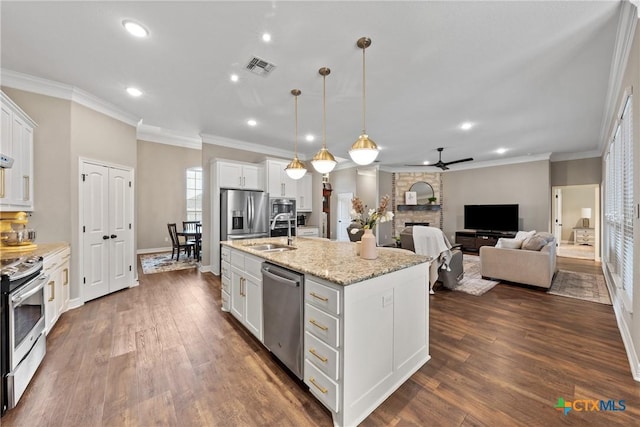 kitchen with visible vents, appliances with stainless steel finishes, a stone fireplace, white cabinetry, and a sink