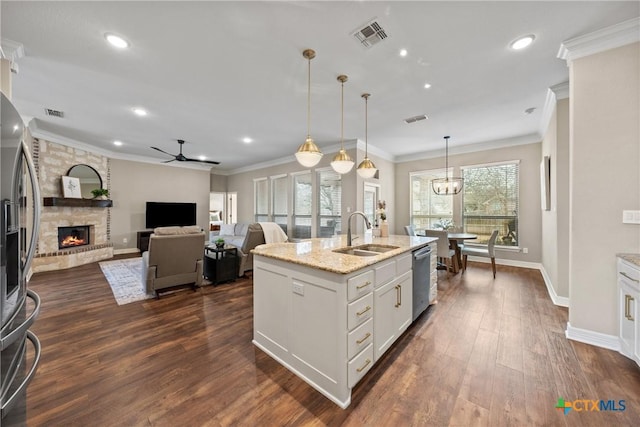 kitchen featuring a stone fireplace, dark wood-style flooring, a sink, visible vents, and light stone countertops