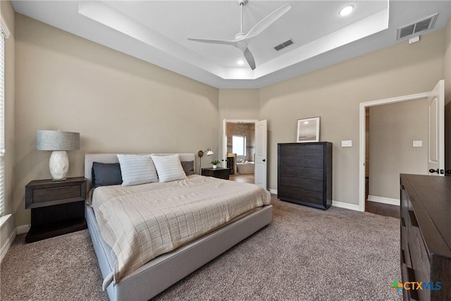 carpeted bedroom with a tray ceiling, visible vents, baseboards, and recessed lighting