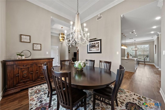 dining space featuring visible vents, a raised ceiling, ornamental molding, dark wood-type flooring, and an inviting chandelier