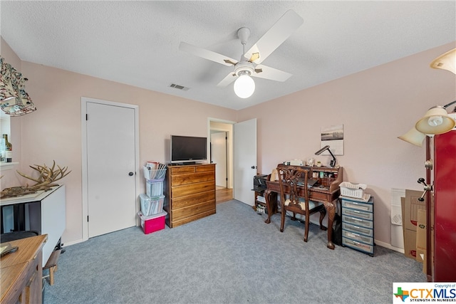 carpeted office space with ceiling fan, a textured ceiling, and visible vents