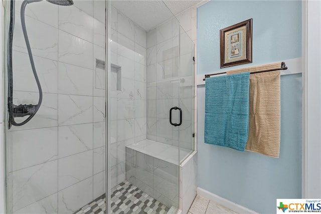 bathroom with a stall shower, baseboards, and a textured ceiling